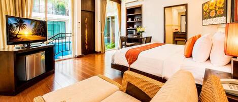 A hotel room with a bed, a desk with a computer, a TV, and a view of the outdoors.