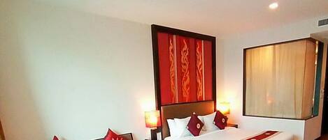 A hotel room with a large bed, a bench, and a nightstand with lamps.
