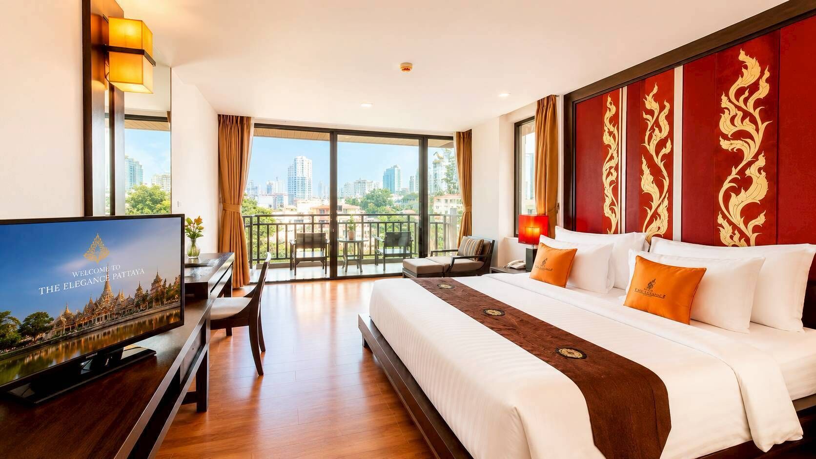 Hotelkamer met een groot bed, een bureau, een televisie en een balkon met uitzicht over de stad.