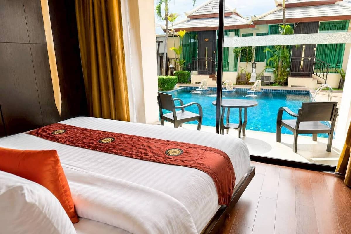 Une chambre d’hôtel avec un lit, une vue sur une piscine et un espace extérieur aménagé pour s’asseoir.