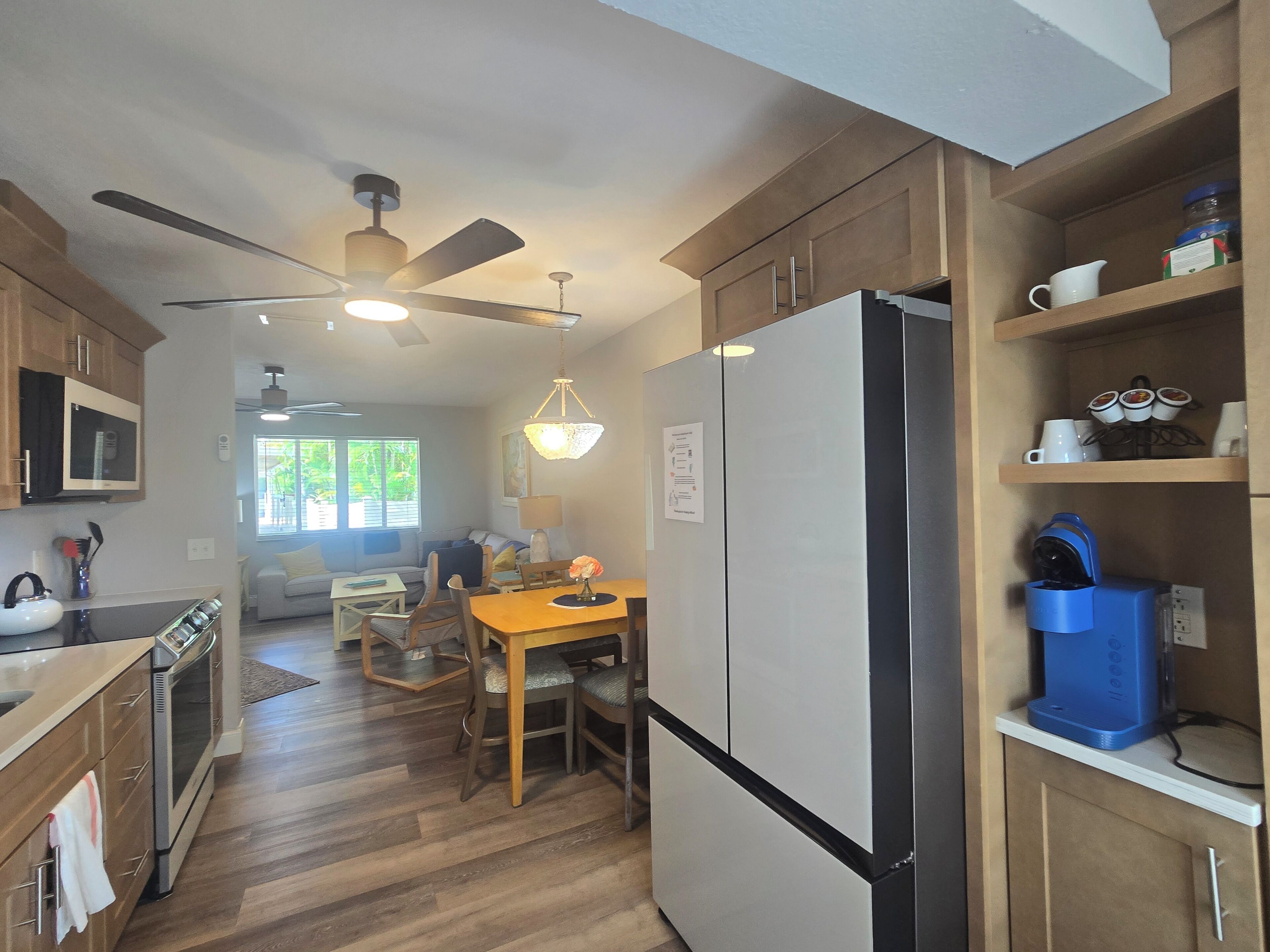 A modern kitchen with wooden cabinets, a stainless steel refrigerator, and a dining area with a table and chairs.