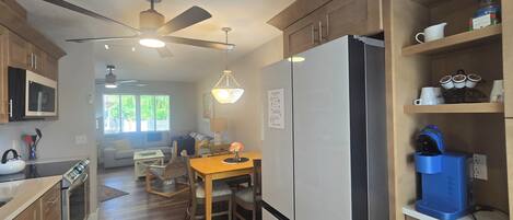 A modern kitchen with wooden cabinets, a stainless steel refrigerator, and a dining area with a table and chairs.