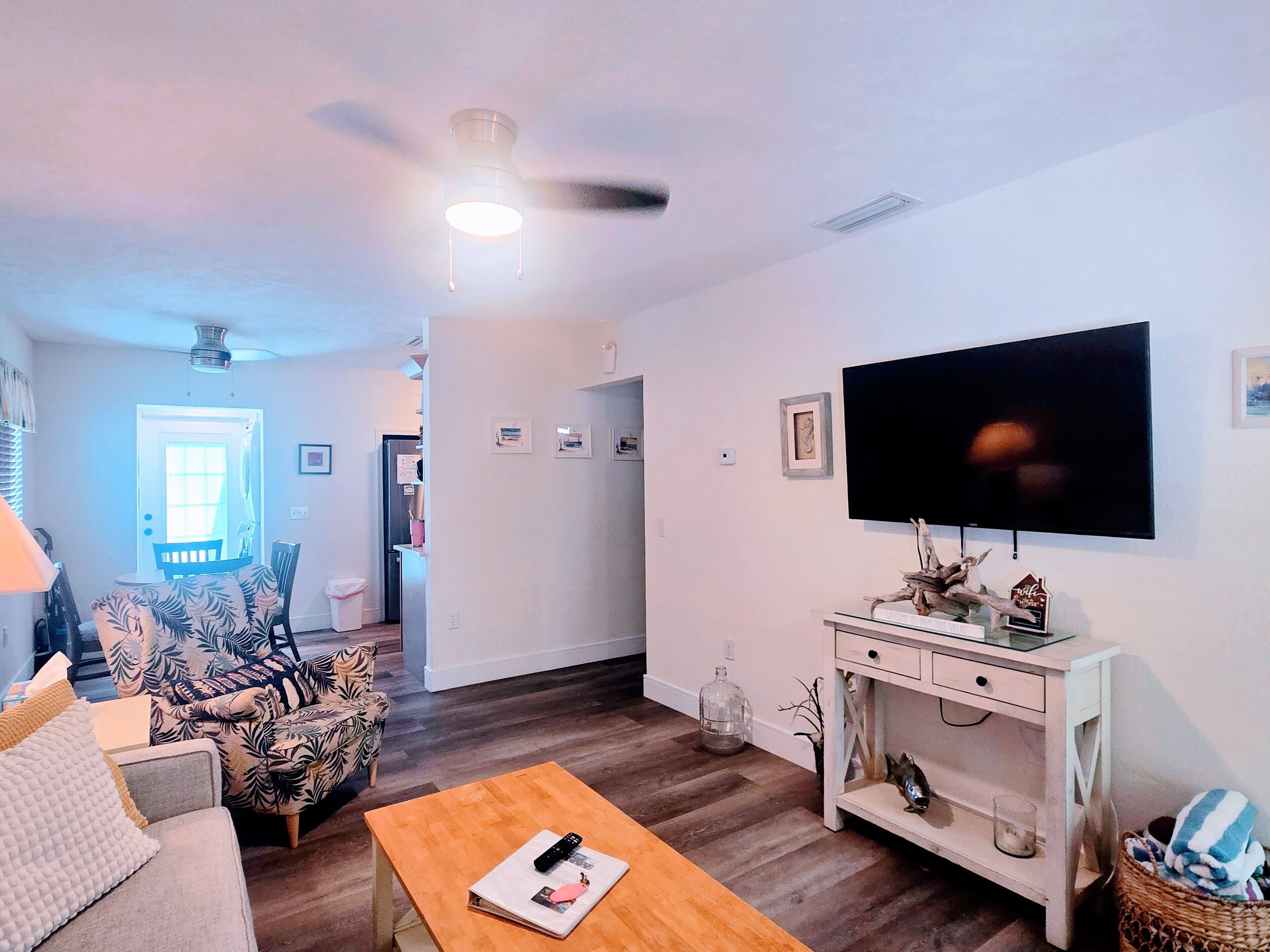 A living room with a sofa, a coffee table, a TV, and a ceiling fan.