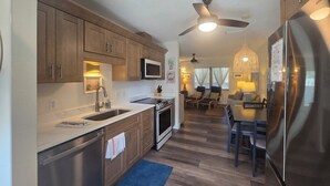 Una cocina moderna con armarios de madera, electrodomésticos de acero inoxidable y una zona de comedor con mesa y sillas.