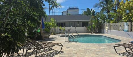 A backyard with a swimming pool, patio furniture, and a wooden fence.