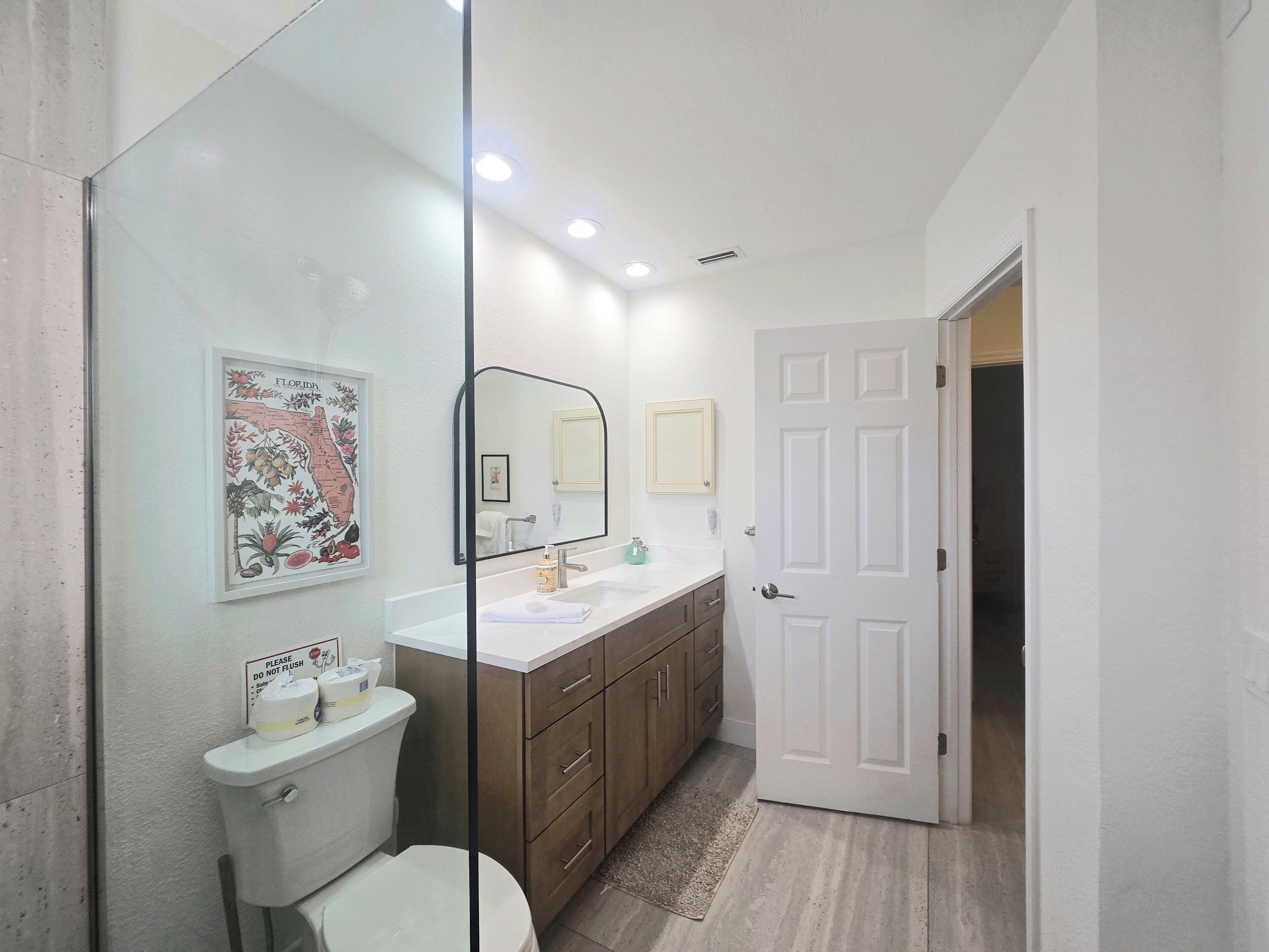 A bathroom with a toilet, sink, mirror, and cabinet.