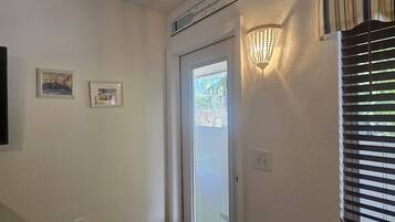Un pasillo con una puerta, una lámpara de pared y dos cuadros enmarcados.