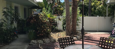 A patio area with a round table and chairs, a large umbrella, and a white fence.