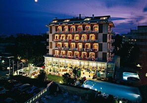 A multi-story hotel with balconies, a pool, and outdoor seating.