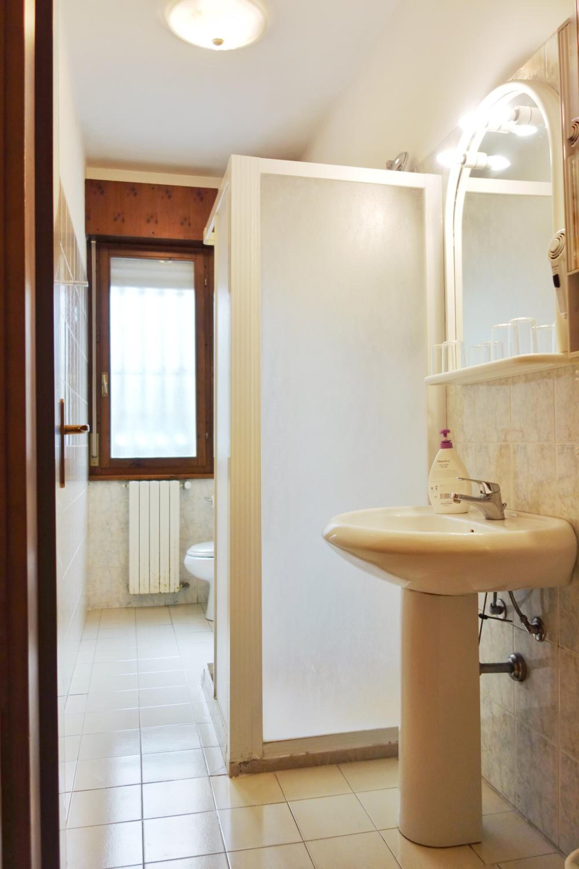 A bathroom with a white sink, a mirror, and a window.