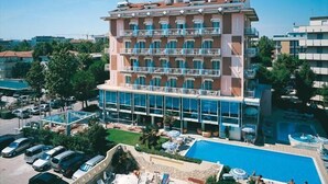 A multi-story hotel with a swimming pool, outdoor seating, and a parking area. - Hotel Tridentum (Cesenatico)