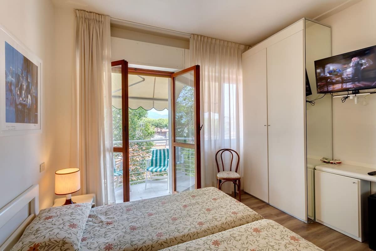 Habitación de hotel con cama, televisión, escritorio y vistas al exterior.