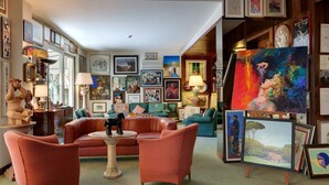 A cozy living room with a fireplace, comfortable seating, and a variety of artwork on the walls. - Hotel Bacco (Camaiore)