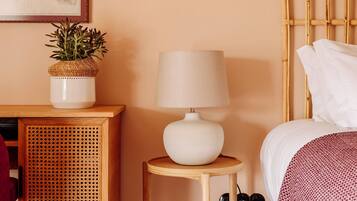 A bedroom with a bed, bedside table, lamp, and a small potted plant.