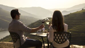 Un couple est assis à une table d’où l’on peut admirer les vignes en terrasses.