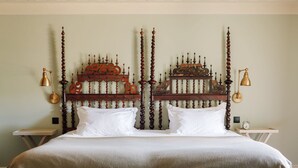 Un lit double avec une tête de lit en bois, deux tables de chevet et une petite table de nuit avec une horloge.