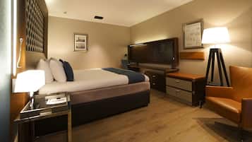 Een hotelkamer met een bed, een bureau, een stoel, een televisie en een lamp.