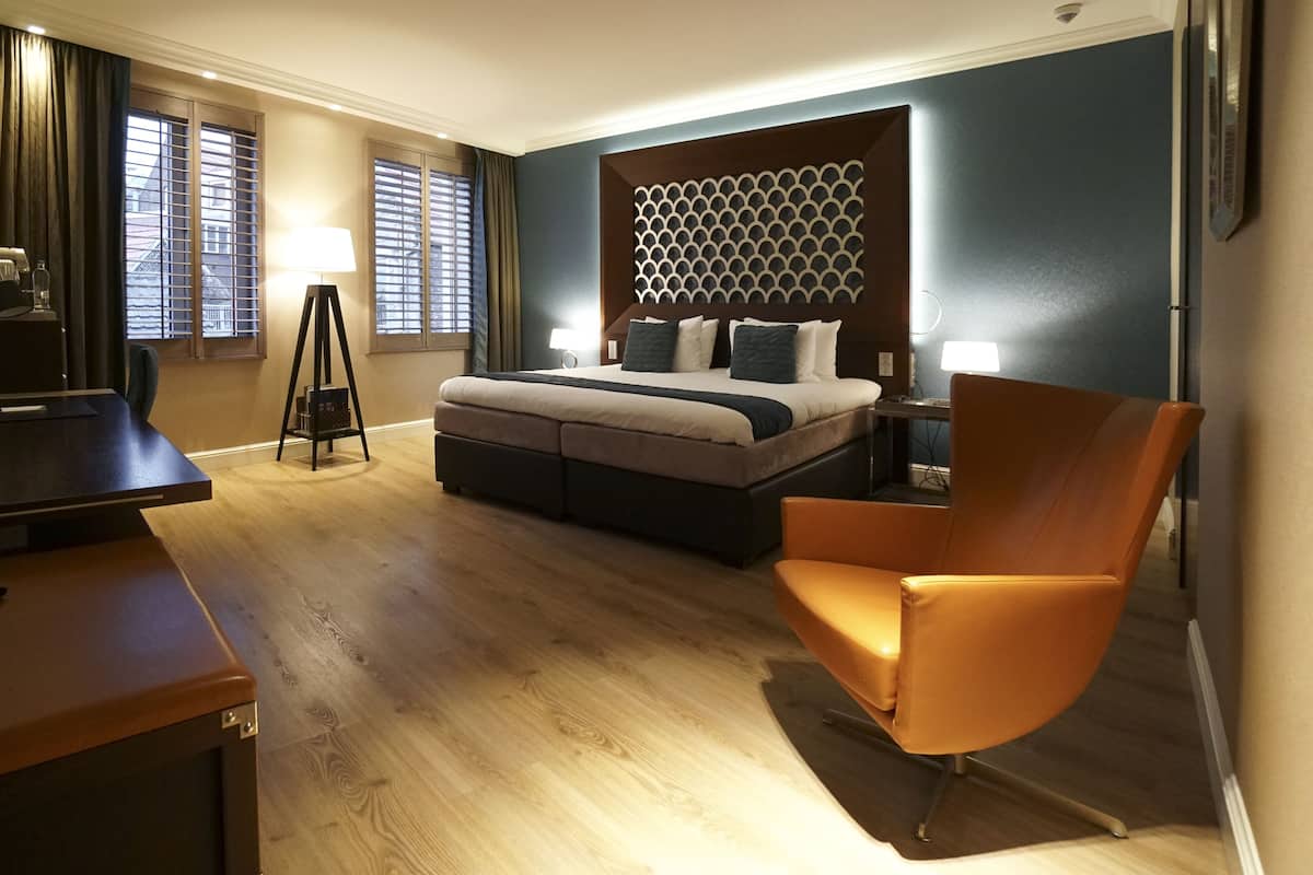 Une chambre d’hôtel avec un lit, un bureau, une chaise et une lampe.