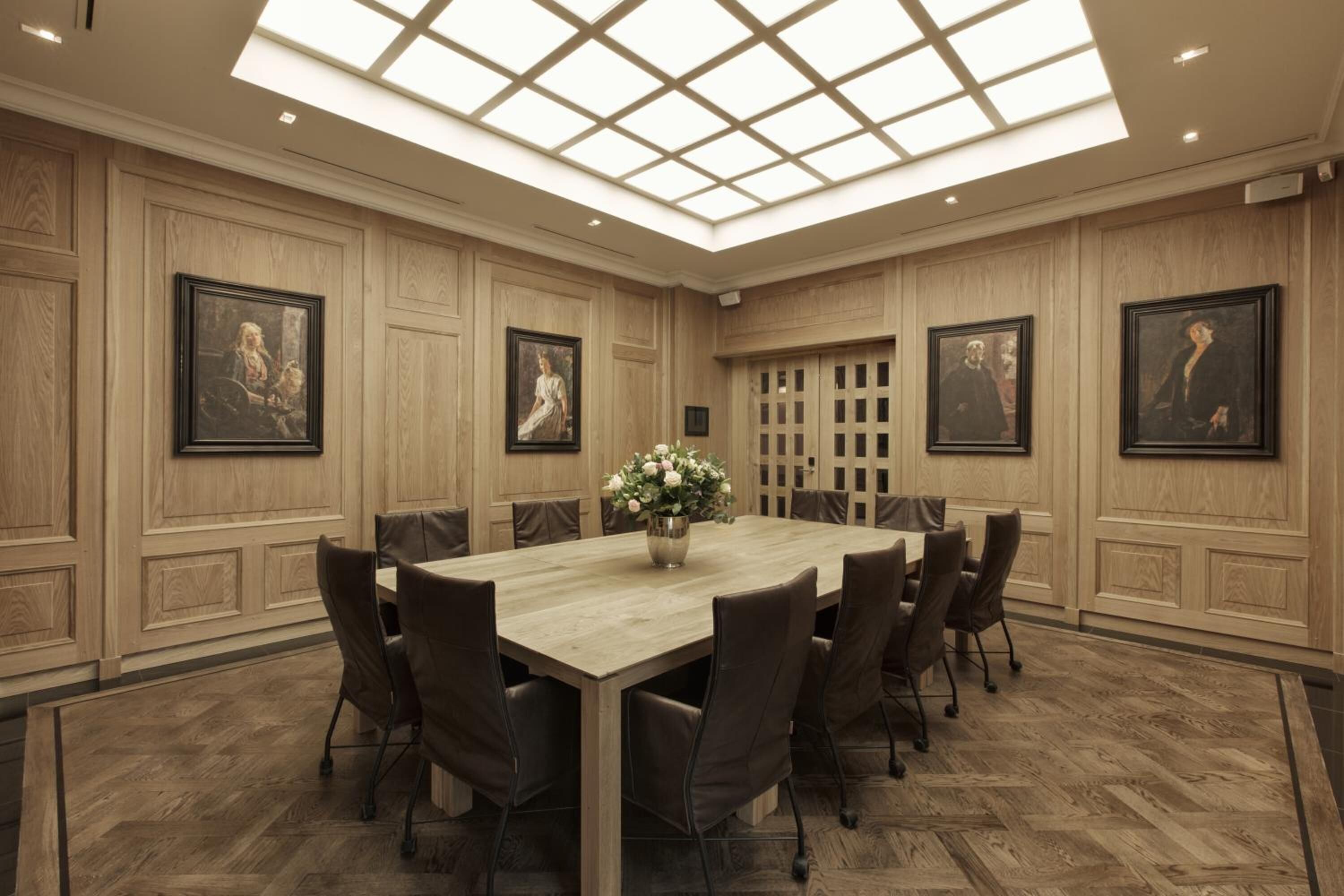 A conference room with a large table, chairs, and framed artwork on the walls.