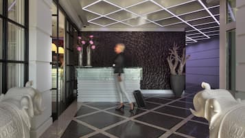 A hotel lobby with a geometric ceiling design, a reception desk, and decorative elephant sculptures.