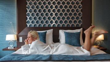 Een hotelkamer met een kamerhoge bekleding met een patroon, een bed met wit- en blauwe beddengoed, en bedlampen.