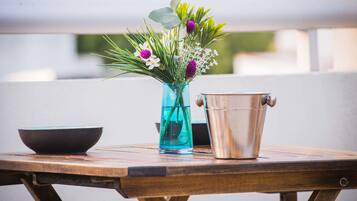 Una mesa de madera con un jarrón azul con flores, un cubo de metal y un bol negro.