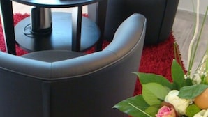 Una habitación moderna con dos sillones de cuero negro, una mesita redonda con una bandeja blanca y un cuenco de naranjas.