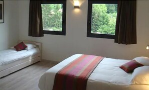A bedroom with two beds, a window, and a wall-mounted light. - Citotel Cote Hotel (Legny)