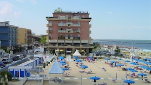 A multi-story hotel with balconies, a beachside location, and a beach with umbrellas and sun loungers. - Baia (Rimini)