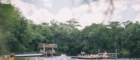 A crowded outdoor swimming area with multiple docks and a viewing platform.