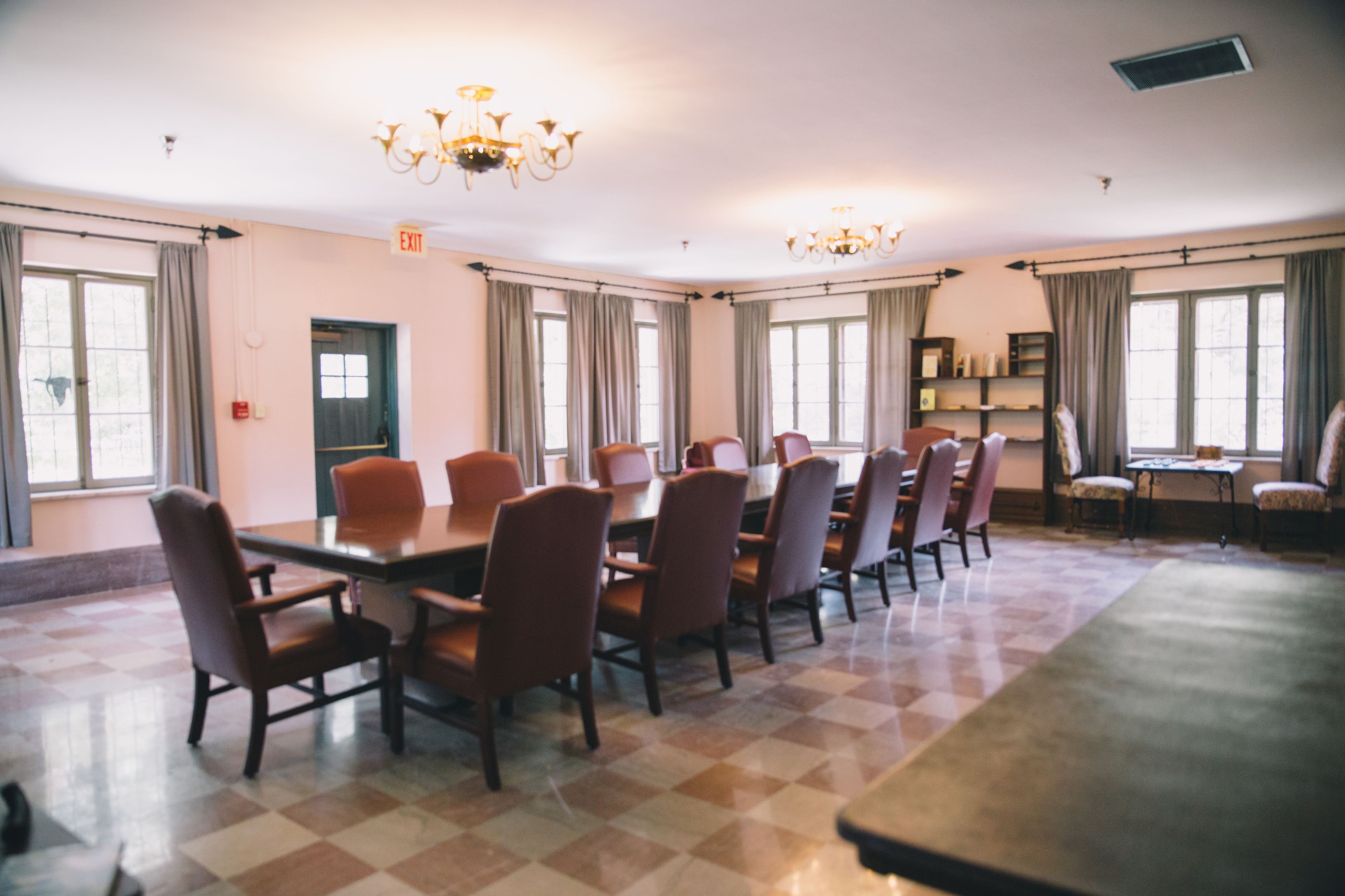Un salón de conferencias con una larga mesa, varias sillas y candelabros.
