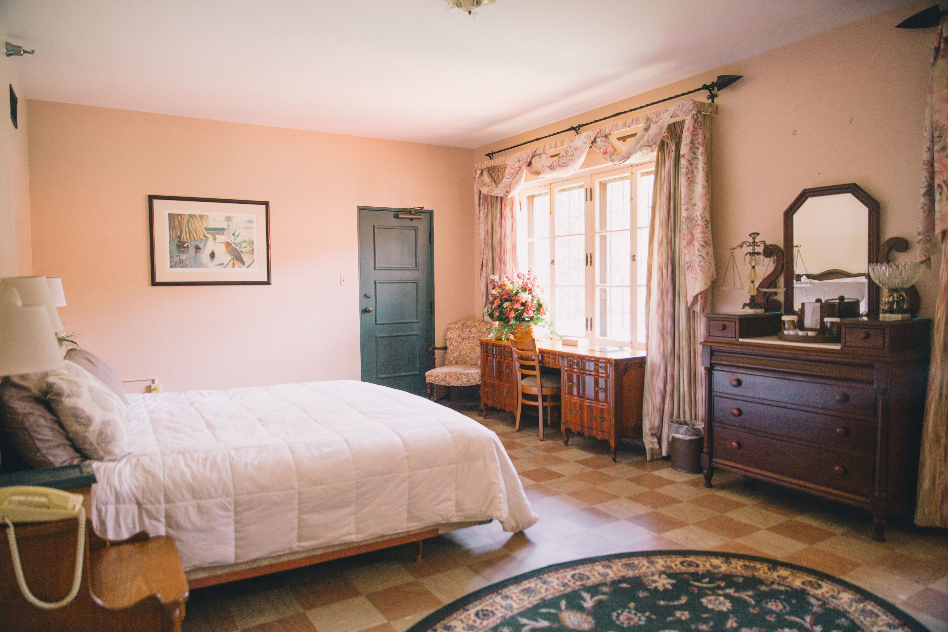 A bedroom with a bed, a desk, a dresser, and a chair.