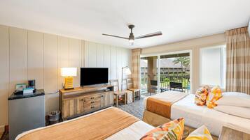 Habitación de hotel con dos camas, televisión, escritorio y vistas al exterior.