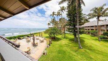 A hotel with a view of the ocean, outdoor seating, and palm trees.