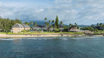 A beachfront hotel with multiple buildings, a sandy beach, and palm trees.