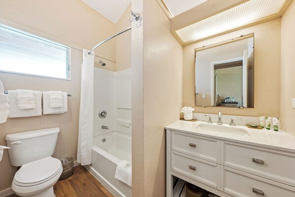 A bathroom with a toilet, shower, and sink area.