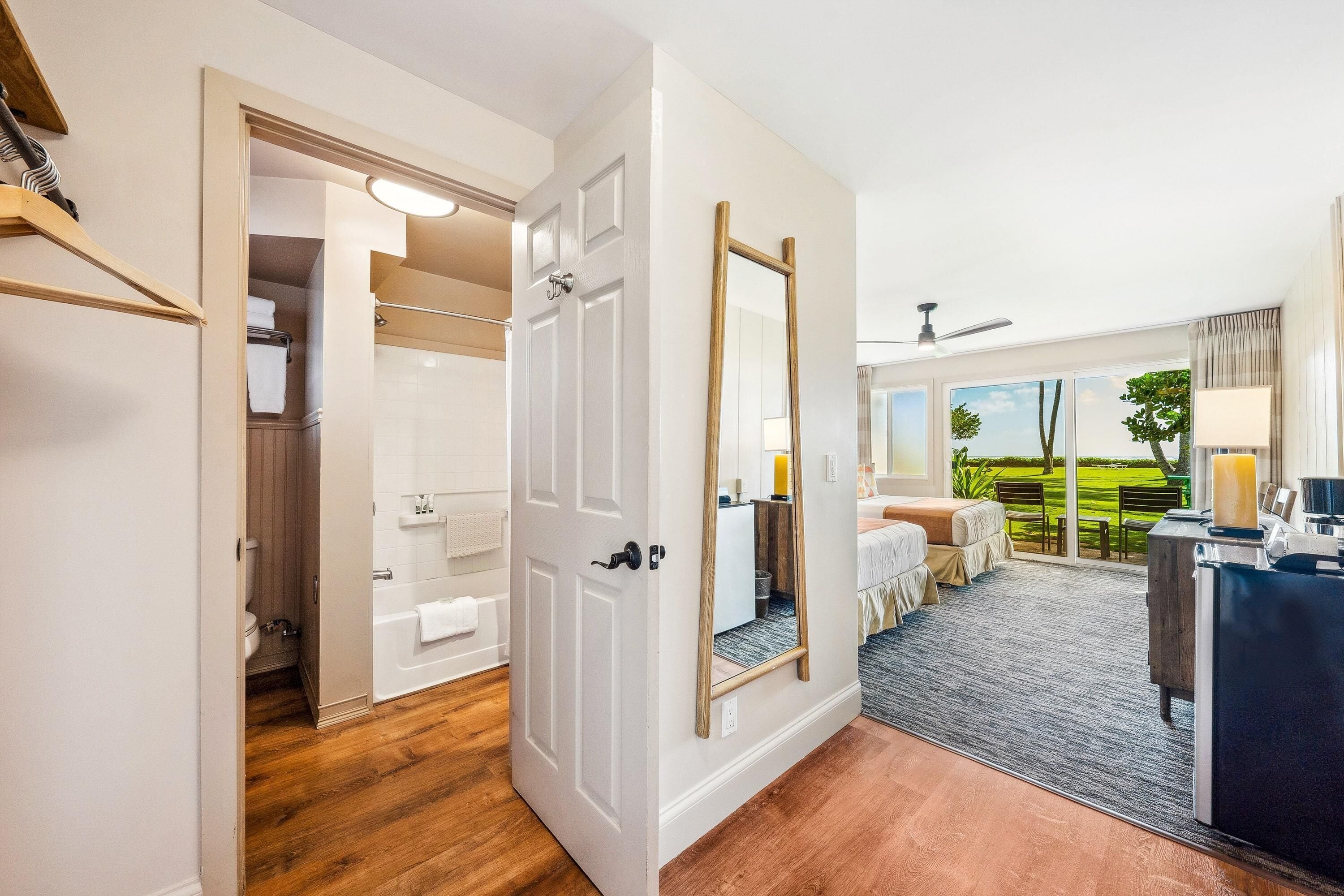 Habitación de hotel con baño, un espejo grande, una cama, un escritorio y vistas al exterior.