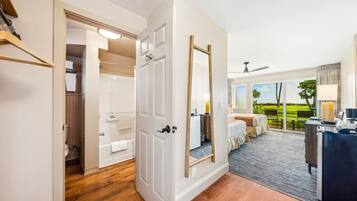 Habitación de hotel con baño, un espejo grande, una cama, un escritorio y vistas al exterior.