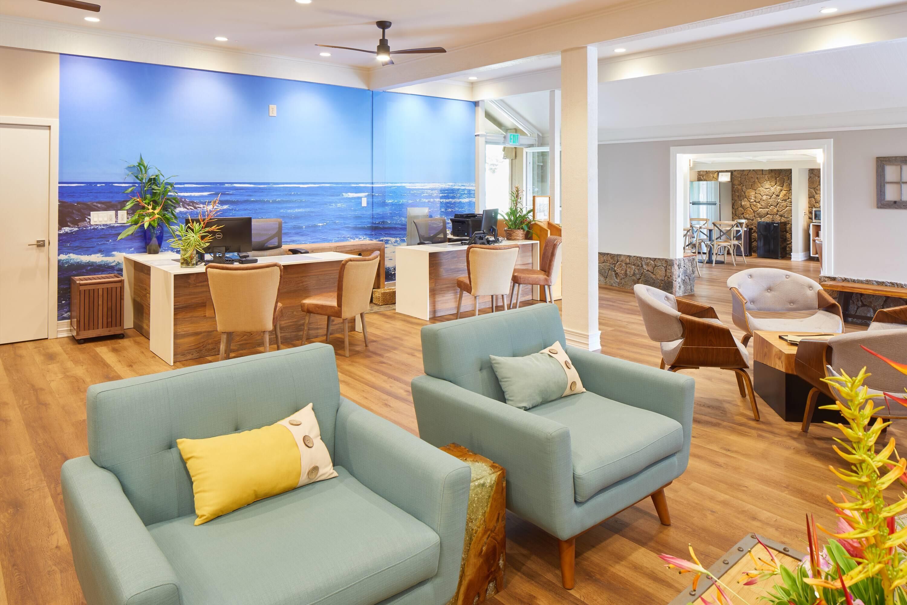 A spacious lobby with a large wall mural of the ocean, comfortable seating, and a reception desk.