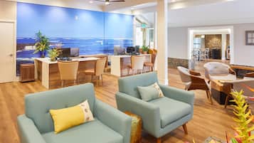 A spacious lobby with a large wall mural of the ocean, comfortable seating, and a reception desk.
