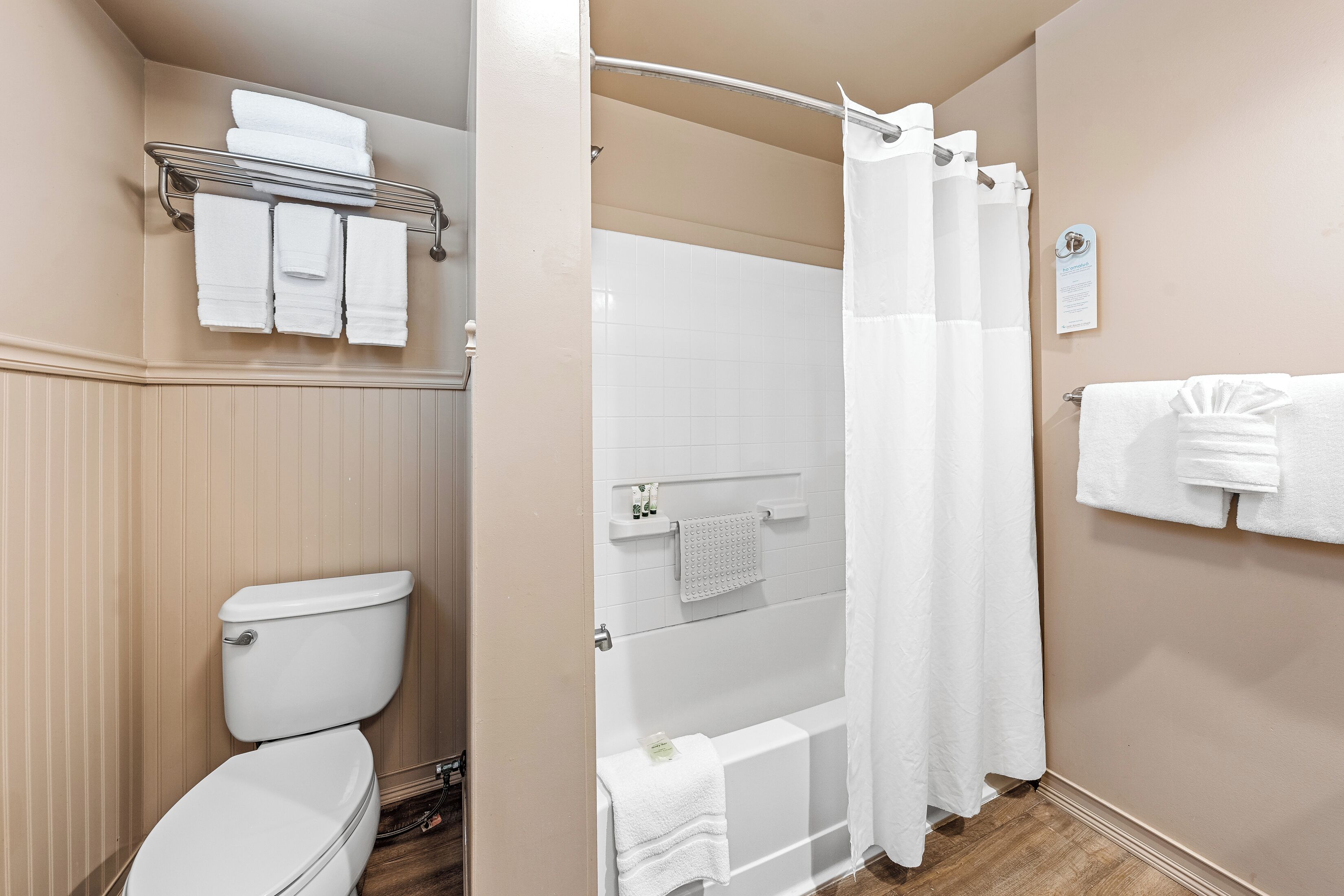 A bathroom with a toilet, shower, and towel rack.