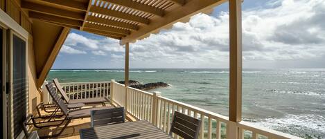 A covered outdoor seating area with a view of the ocean.