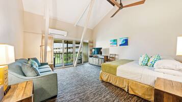 A bedroom with a bed, a sofa, a TV, and a balcony.
