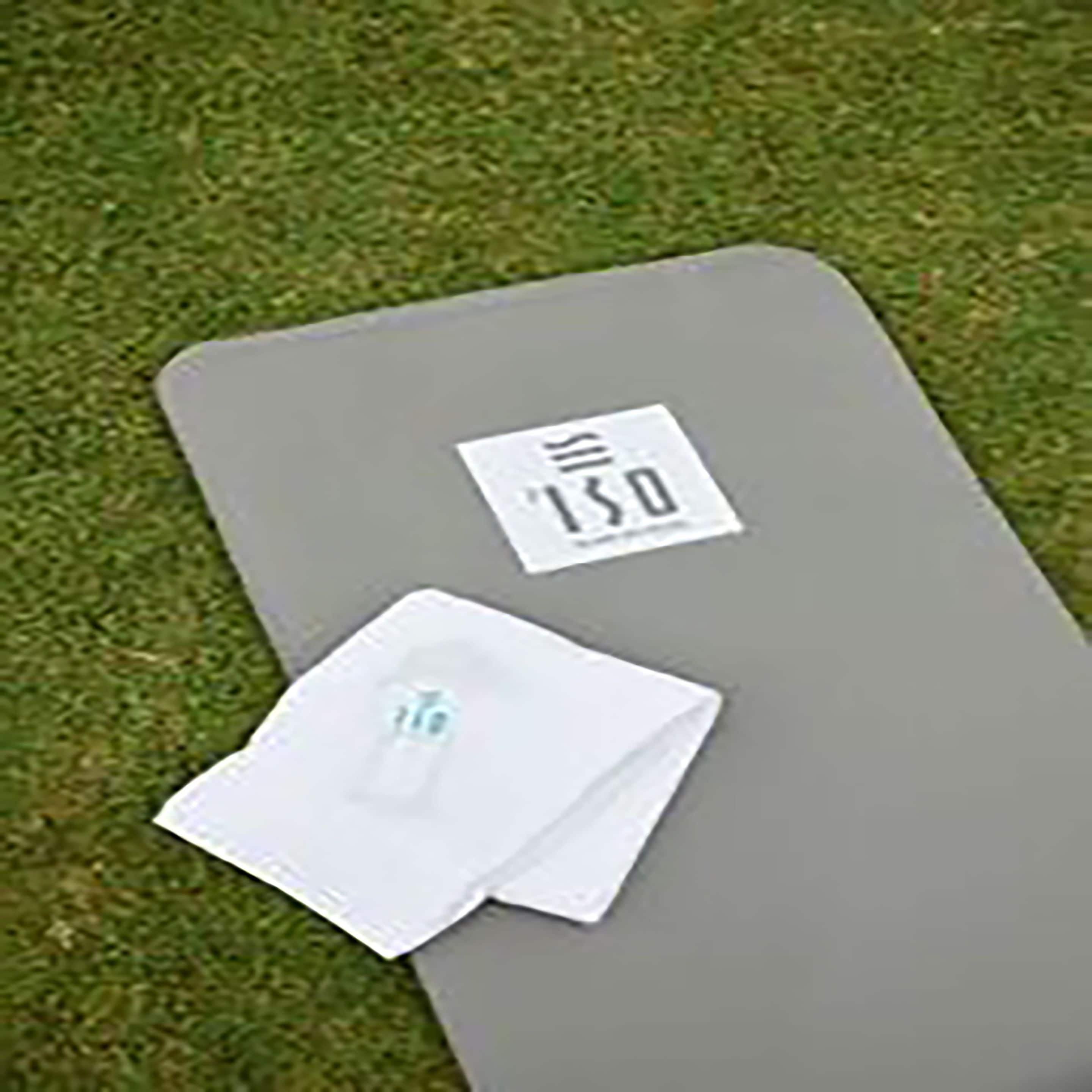 A gray mat with a white label on a grassy surface.
