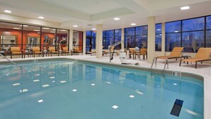 Une piscine intérieure dotée de chaises longues et d’un espace dédié aux bains de soleil.