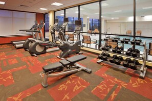 A gym with treadmills, ellipticals, and dumbbells.