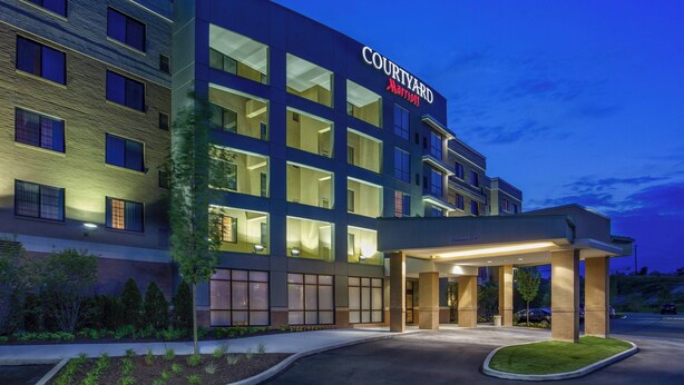 Un hôtel Courtyard Marriott doté d’une façade moderne, de grandes fenêtres et d’une entrée bien éclairée.