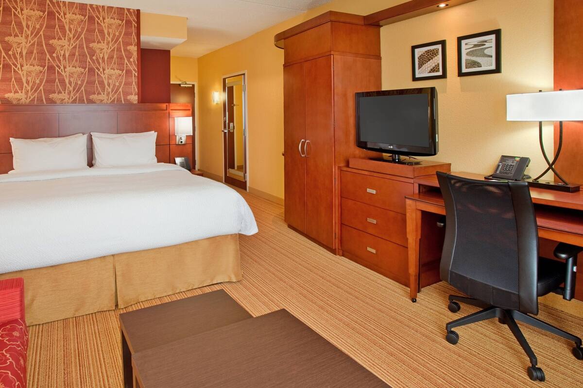 Een hotelkamer met een groot bed, een bureau met een computer, een televisie en een telefoon.