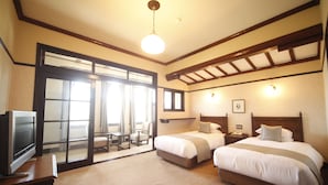 Une chambre d’hôtel avec deux lits, une télévision, un bureau et un balcon avec vue.