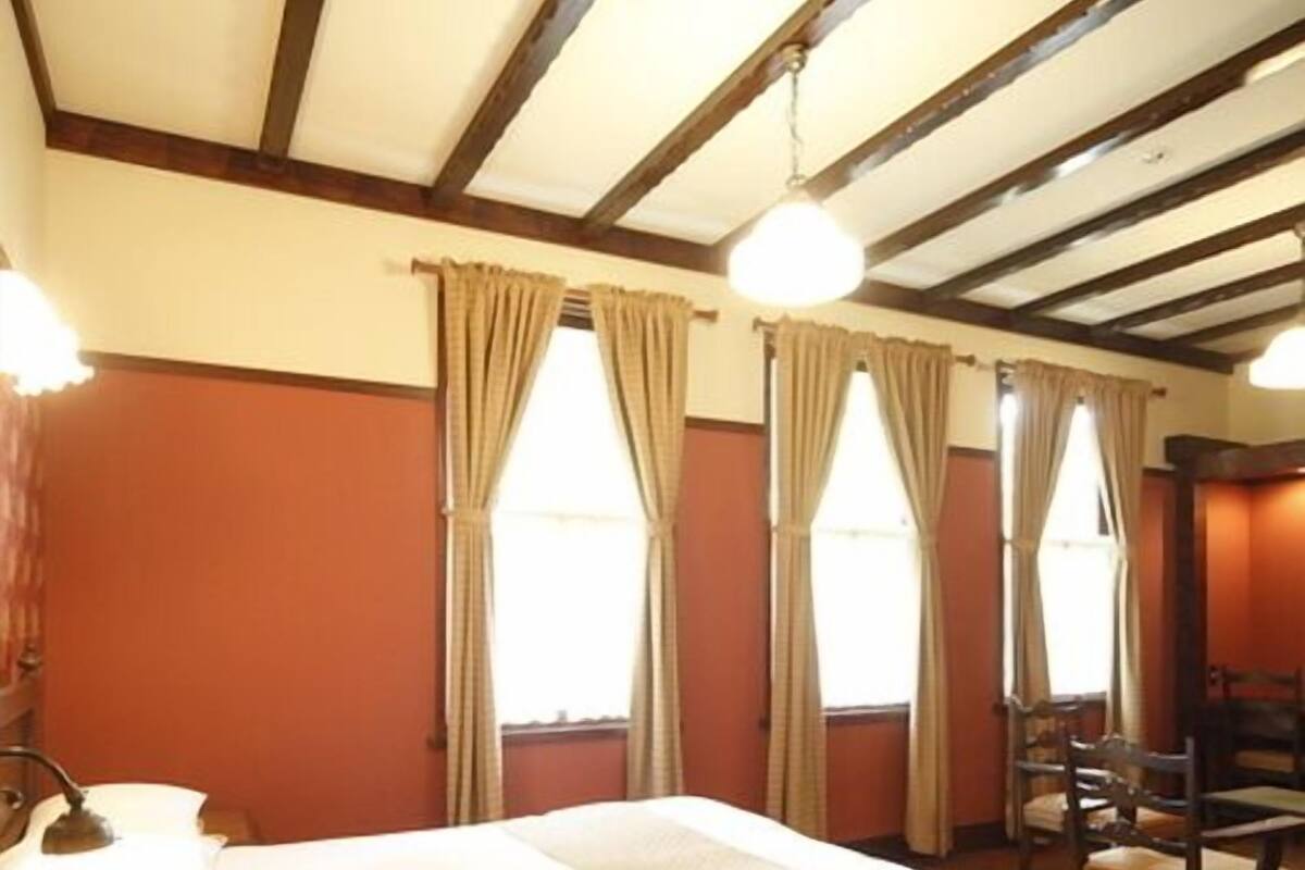 A hotel room with a bed, a desk, a chair, and a window with curtains.